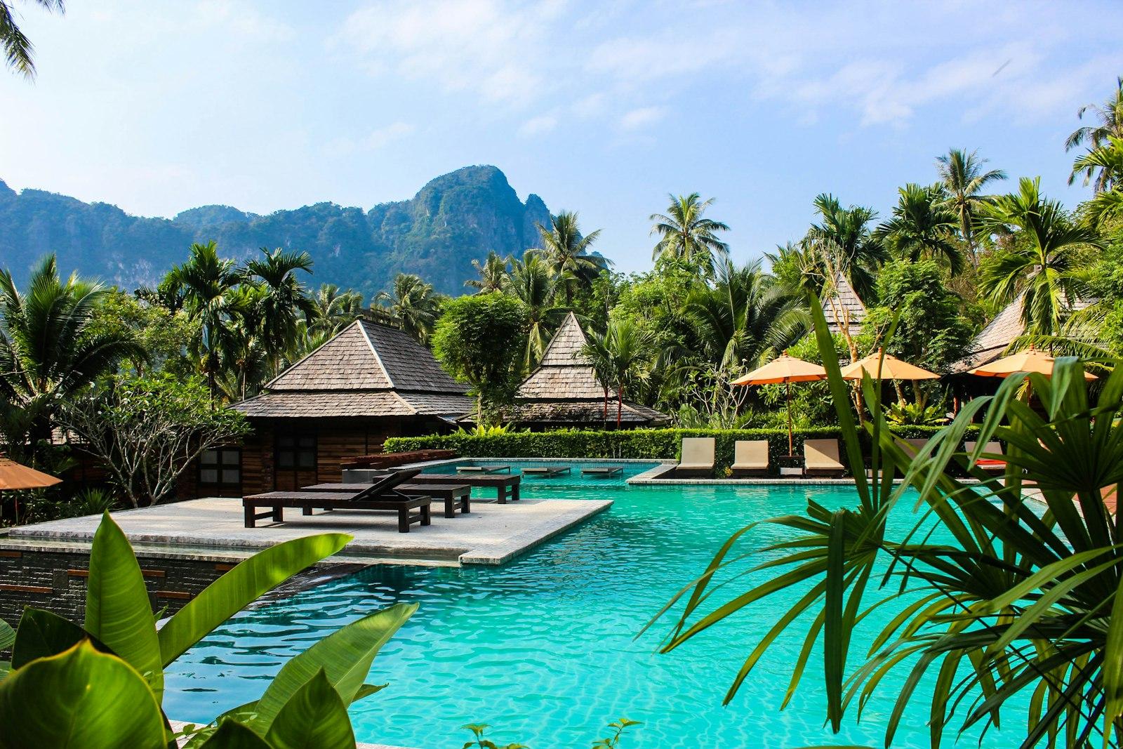 A resort pool surrounded by palm trees and limestone hills